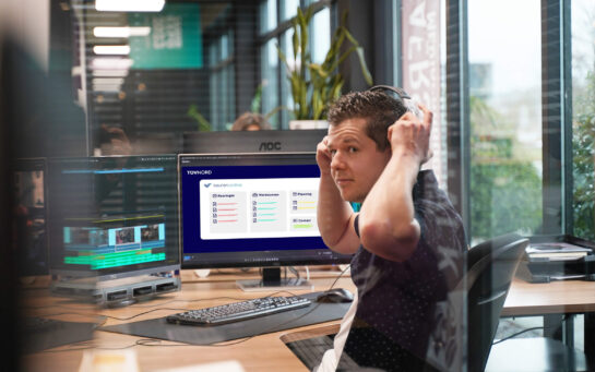 René met headset werkt op een computer met het TÜV Nord keuringsplatform open.
